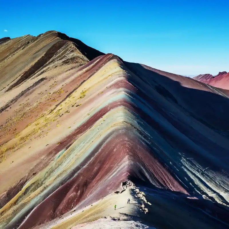 Hikers admiring Rainbow Mountain Peru with panoramic view of colorful Andes